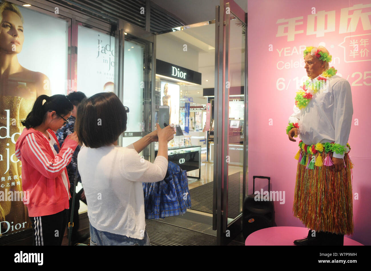 Customers take photos of a wax figure of U.S. President Donald Trump decorated with a grass skirt with a special facial expression at a shopping mall Stock Photo