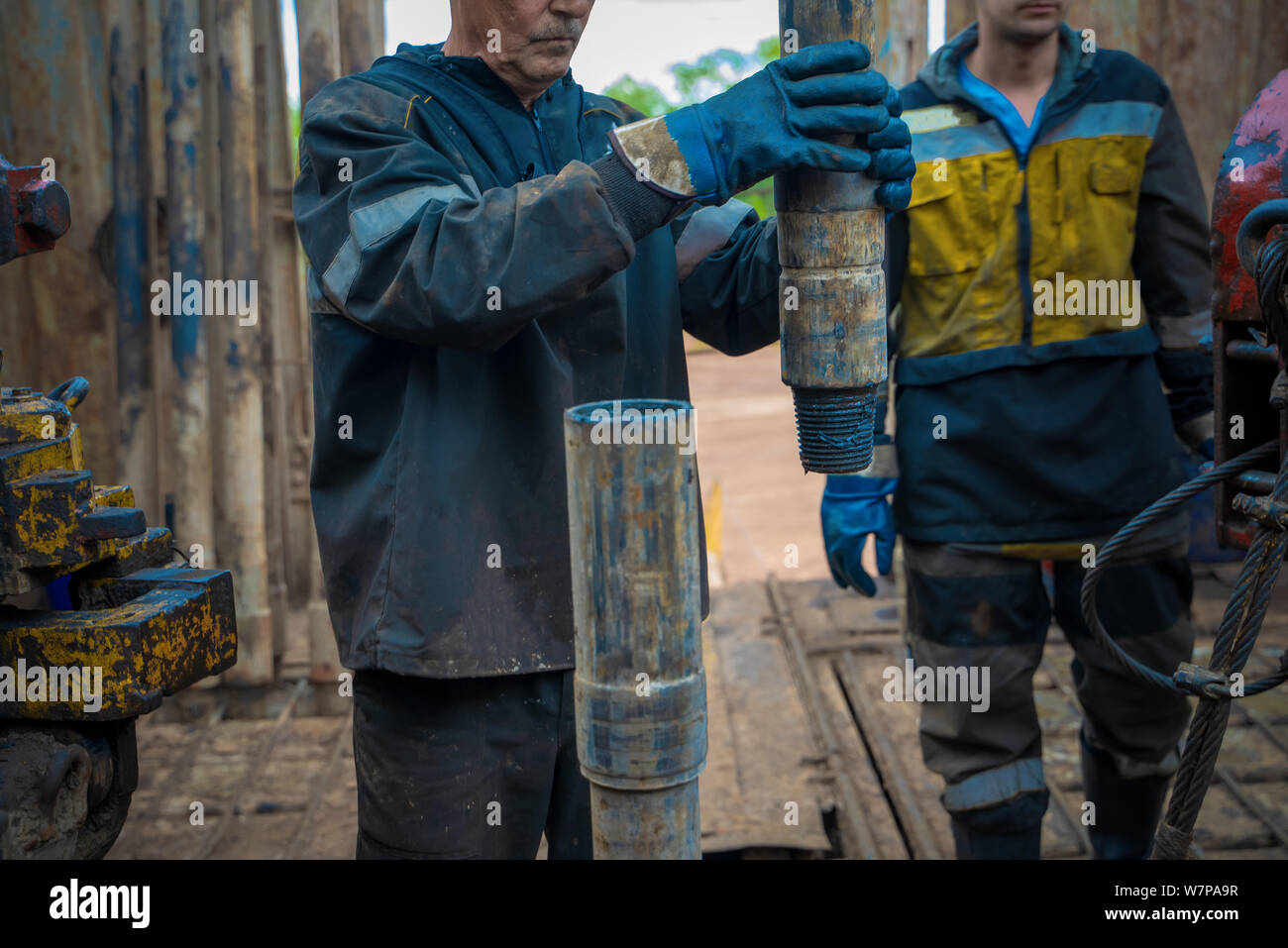 Offshore oil rig worker prepare tool and equipment for perforation oil and gas well at wellhead platform. Making up a drill pipe connection. A view fo Stock Photo