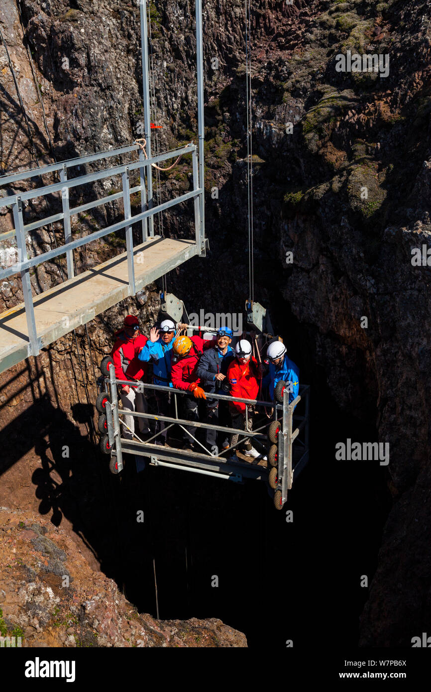 Tourists being lowered into Thrihnukagigur volcano, a dormant volcano now used for tours, by cable lift. Iceland, Europe, June 2012 Stock Photo