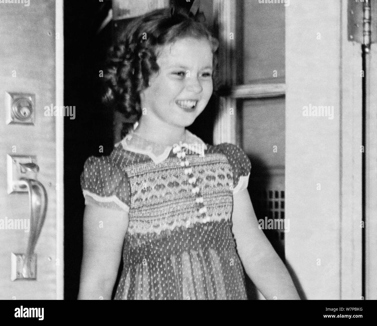 Vintage photo of American child film star Shirley Temple (1928 – 2014). The image was captured on June 24 1938 as the young actress left the White House following a meeting with US President Franklin D Roosevelt. During their conversation she told the President how she had lost a tooth the night before when it fell out as she ate a sandwich. Stock Photo