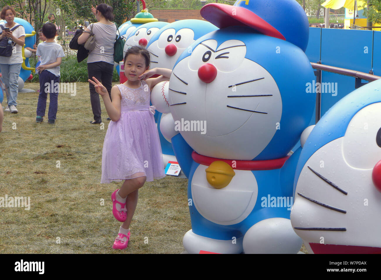 A visitor takes photos with models of Doraemon, a famous Japanese cartoon character, during an exhibition featuring A visitor takes photos with models of Doraemon, a famous Japanese cartoon character, during an exhibition featuring