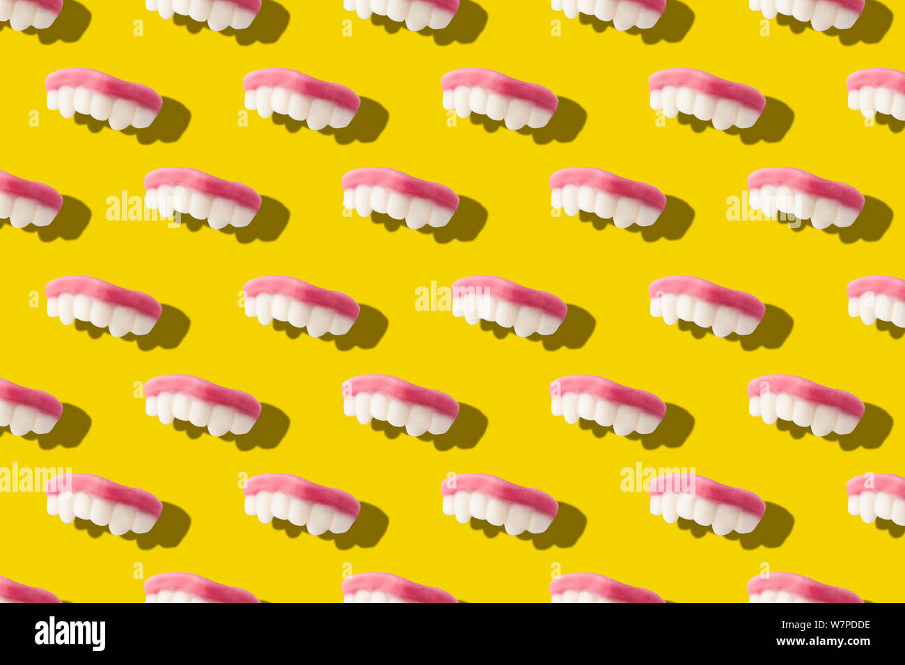 Photography collage of gummy milk teeth or jelly candies on bold yellow background top view flat lay isometric seamless pattern.Funny children's treat Stock Photo