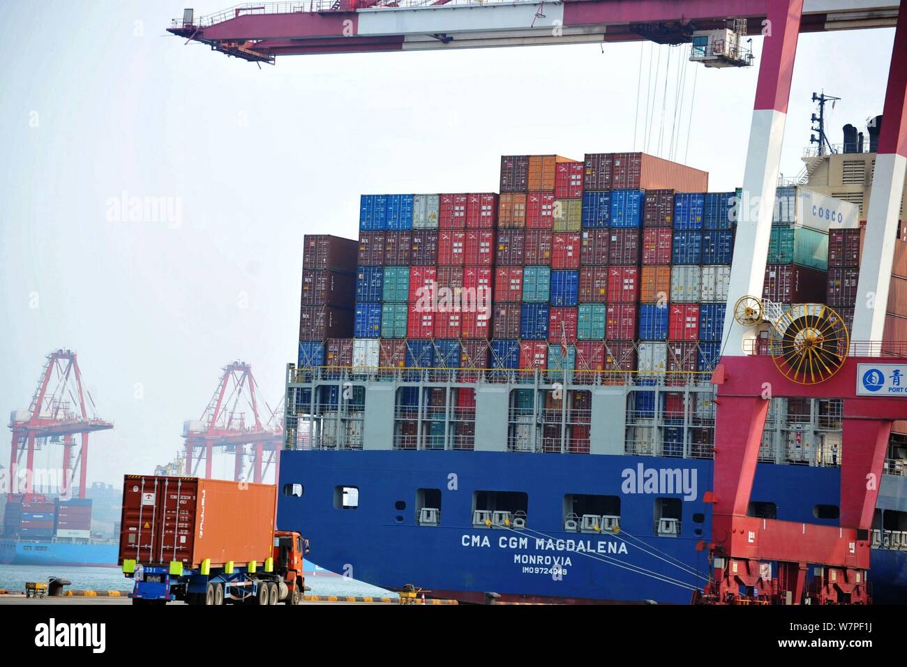 A crane vehicle lifts containers to be shipped abroad from trucks on a quay at the Port of Qingdao in Qingdao city, east China's Shandong province, 7 Stock Photo