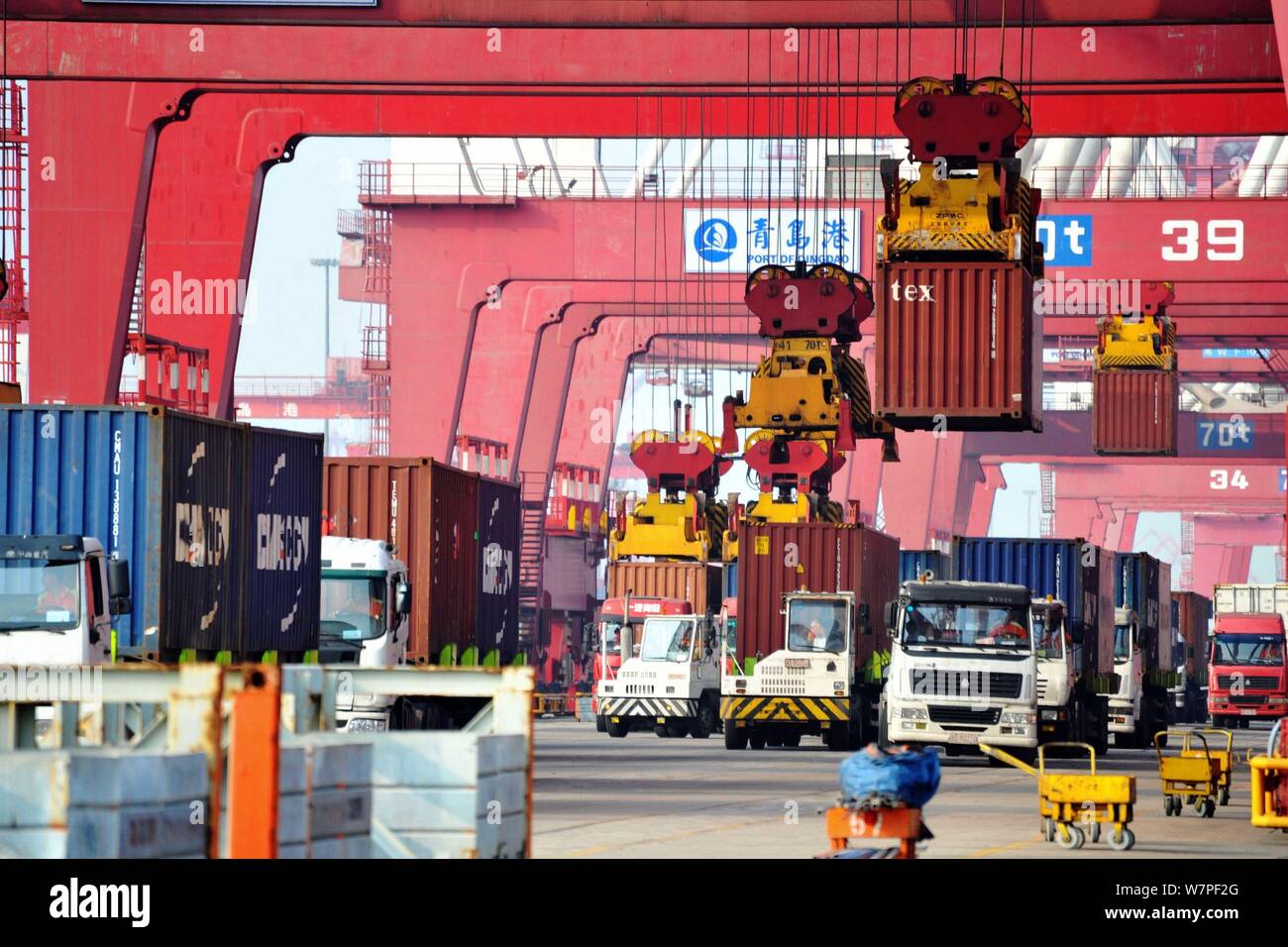 A crane vehicle lifts containers to be shipped abroad from trucks on a quay at the Port of Qingdao in Qingdao city, east China's Shandong province, 7 Stock Photo