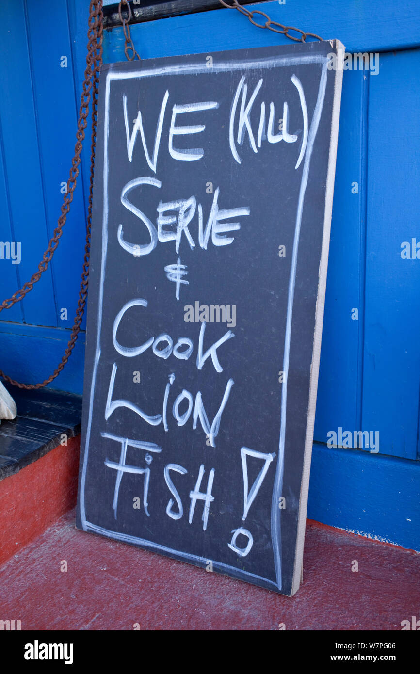 Sign outside Cactus Blue restaurant saying 'We (kill) serve and cook lionfsh!' Lionfish is an invasive species in this region. Kralendijk, Bonaire, Caribbean Stock Photo