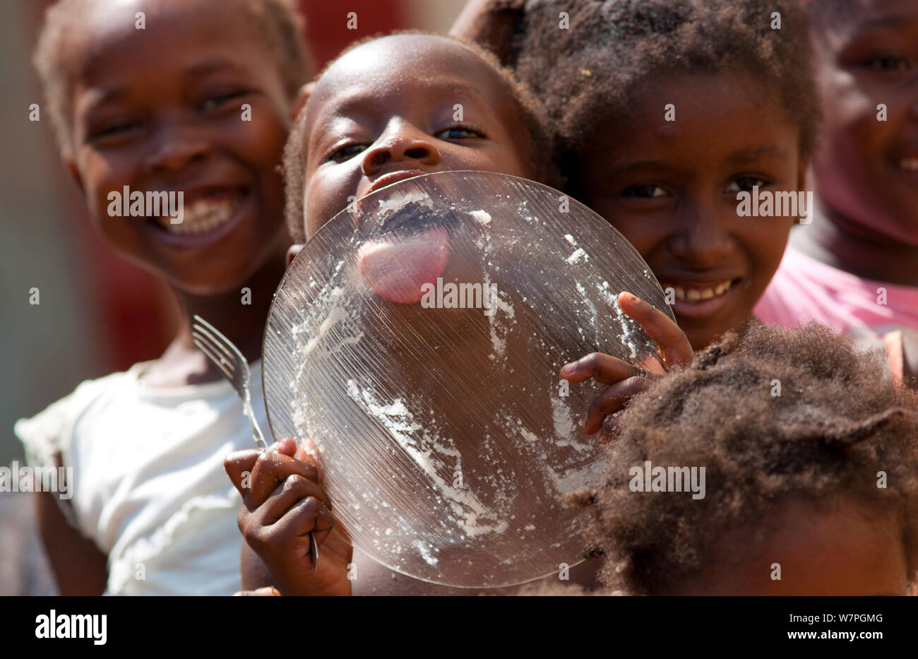 A hungry girl licking plate clean, at a street market vendor in the city of Sao Tomeon the Atlantic Ocean islands of Sao Tome & Principe, February 2009 Stock Photo