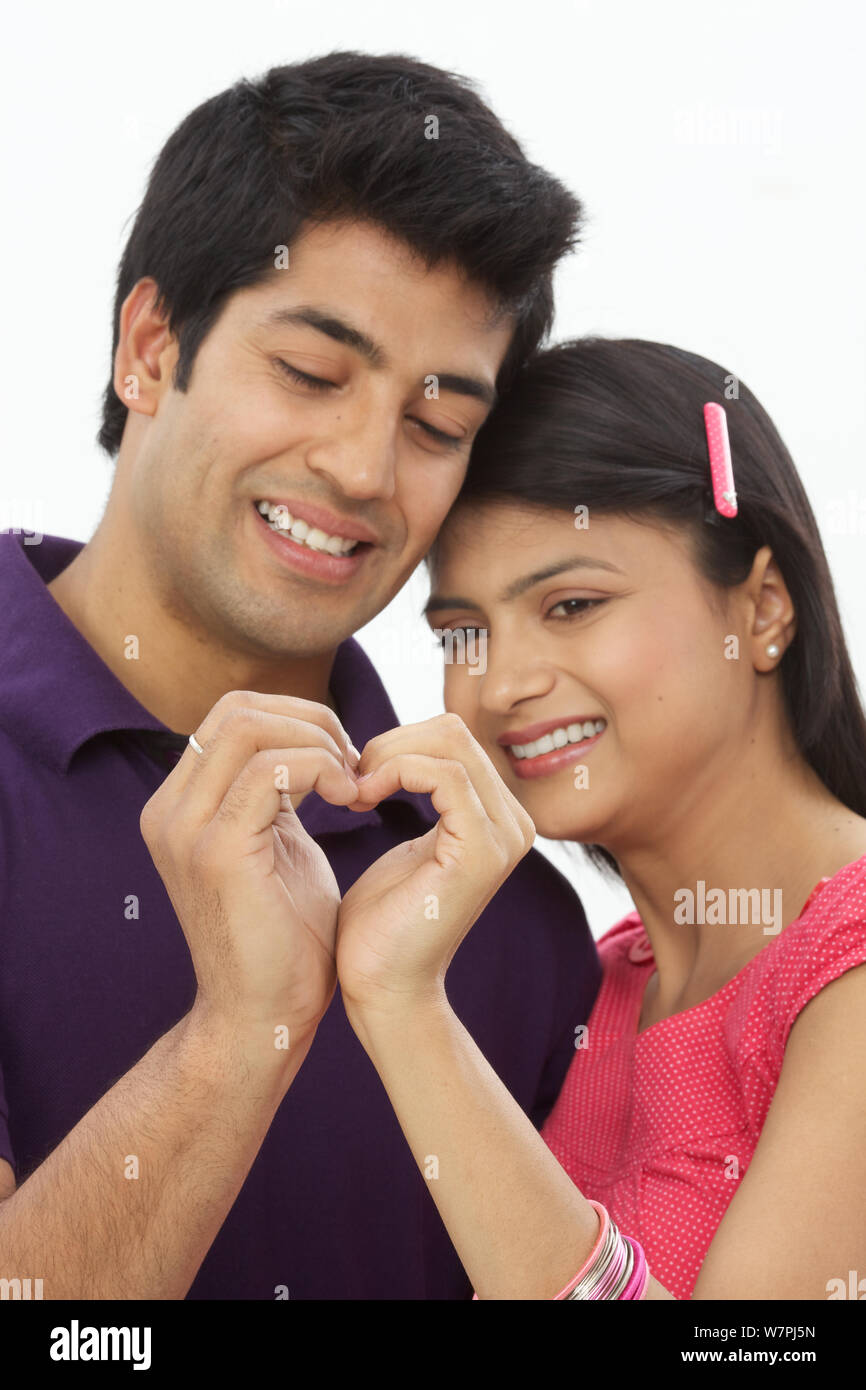 Young couple making heart shape with hands and smiling Stock Photo - Alamy