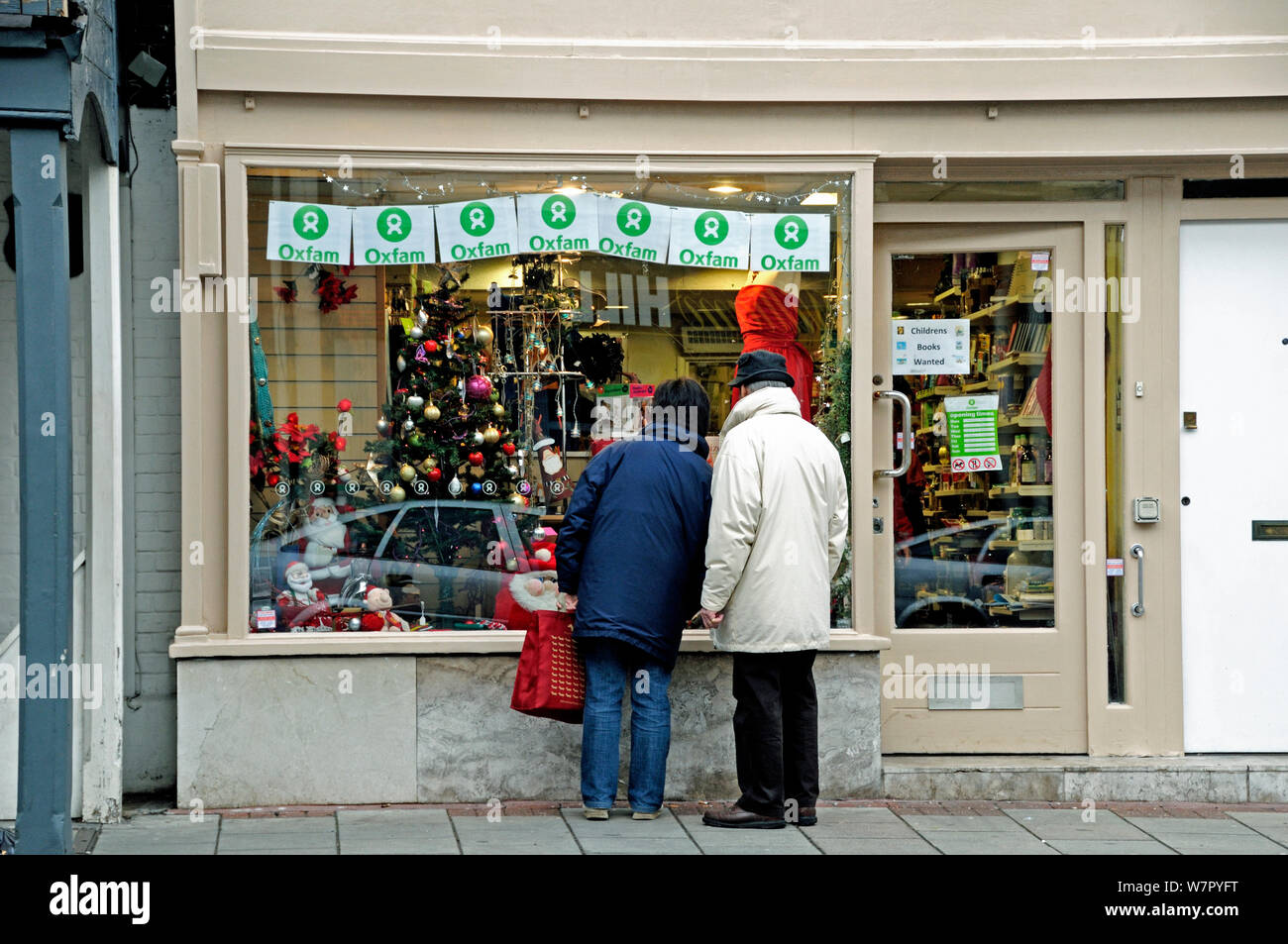 Couple outside Oxfam Shop, just before Christmas, Highgate Village London, England, UK, December 2009 Stock Photo