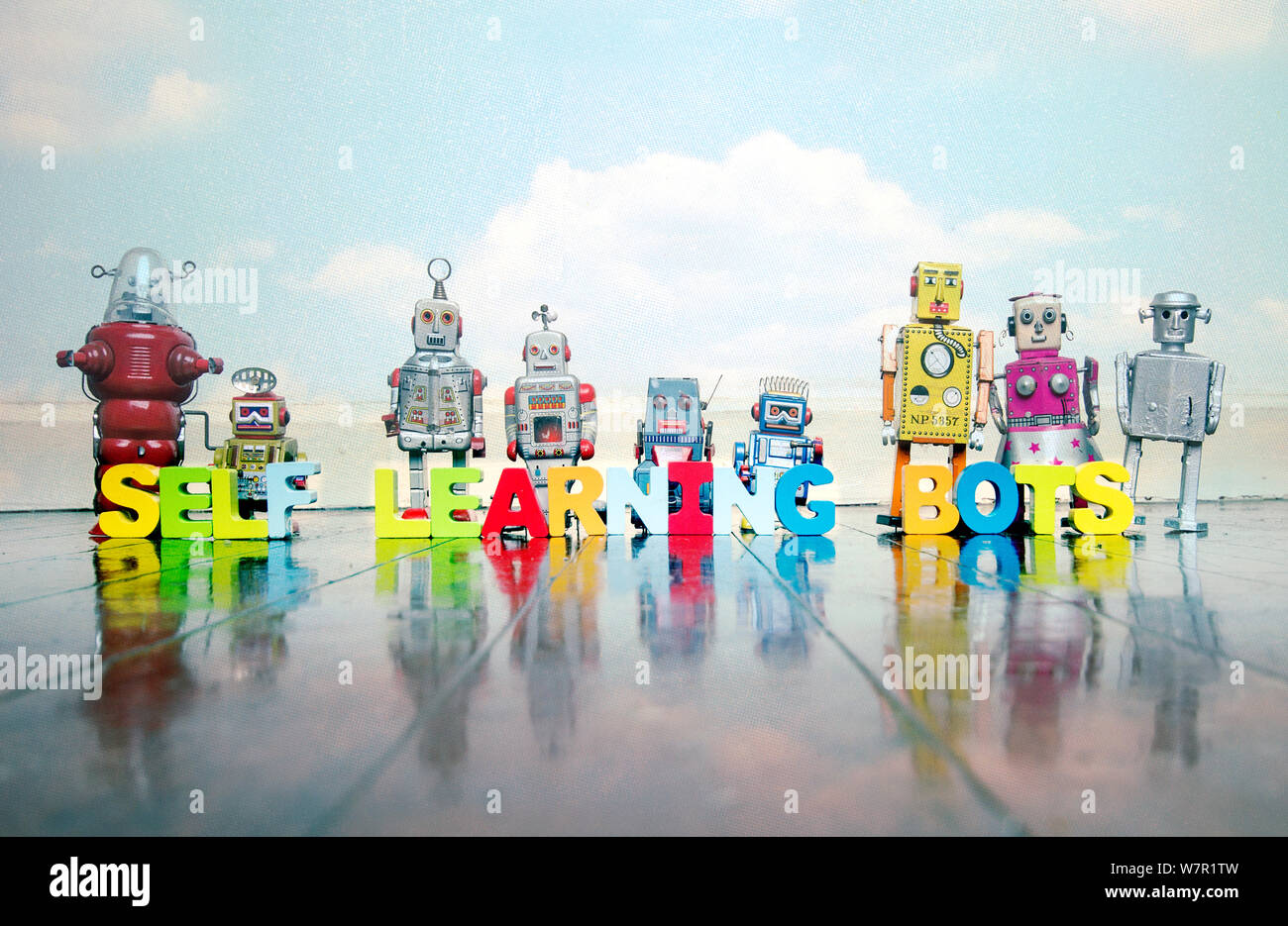 SELF LEARNING BOTS wooden letters and retro robot toys on a wooden floor with reflection Stock Photo