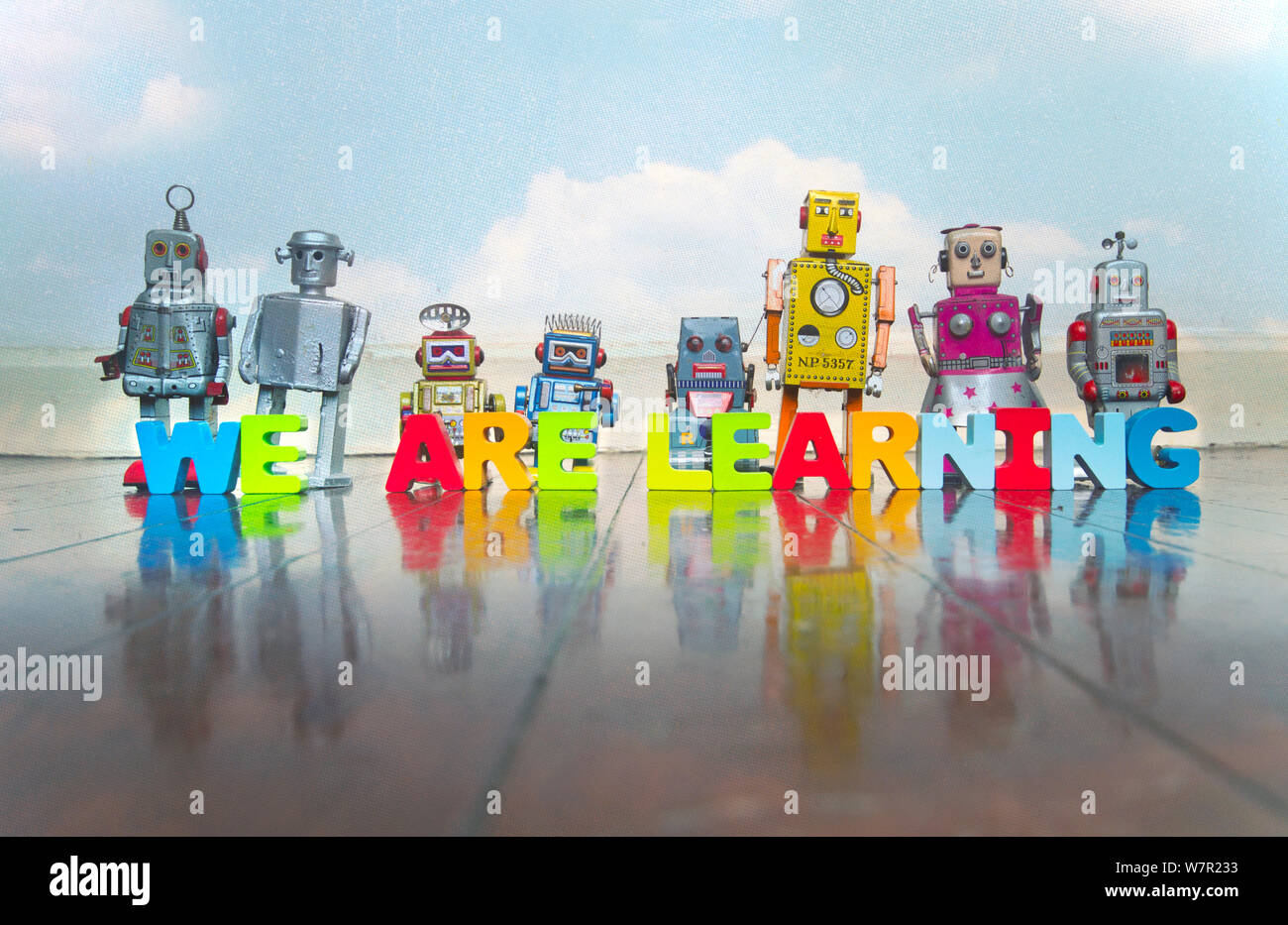 WE ARE LEARNING wooden letters and retro robot toys on a wooden floor with reflection Stock Photo