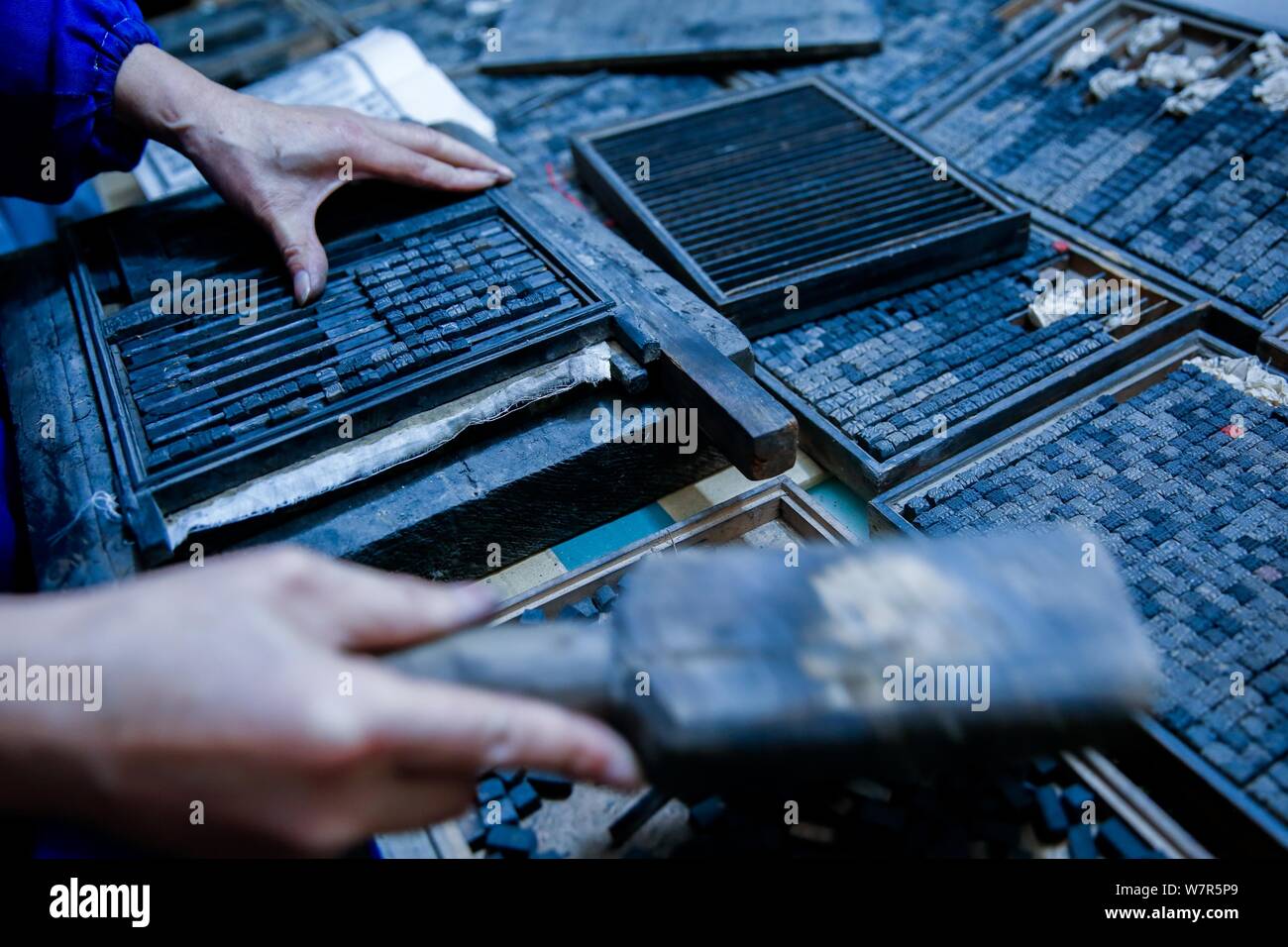 Chinese craftsman Xiao Shihua puts wood typeheads into a plate for movable type printing in Zhulin village, Tantou town, Shaoyang city, central China' Stock Photo