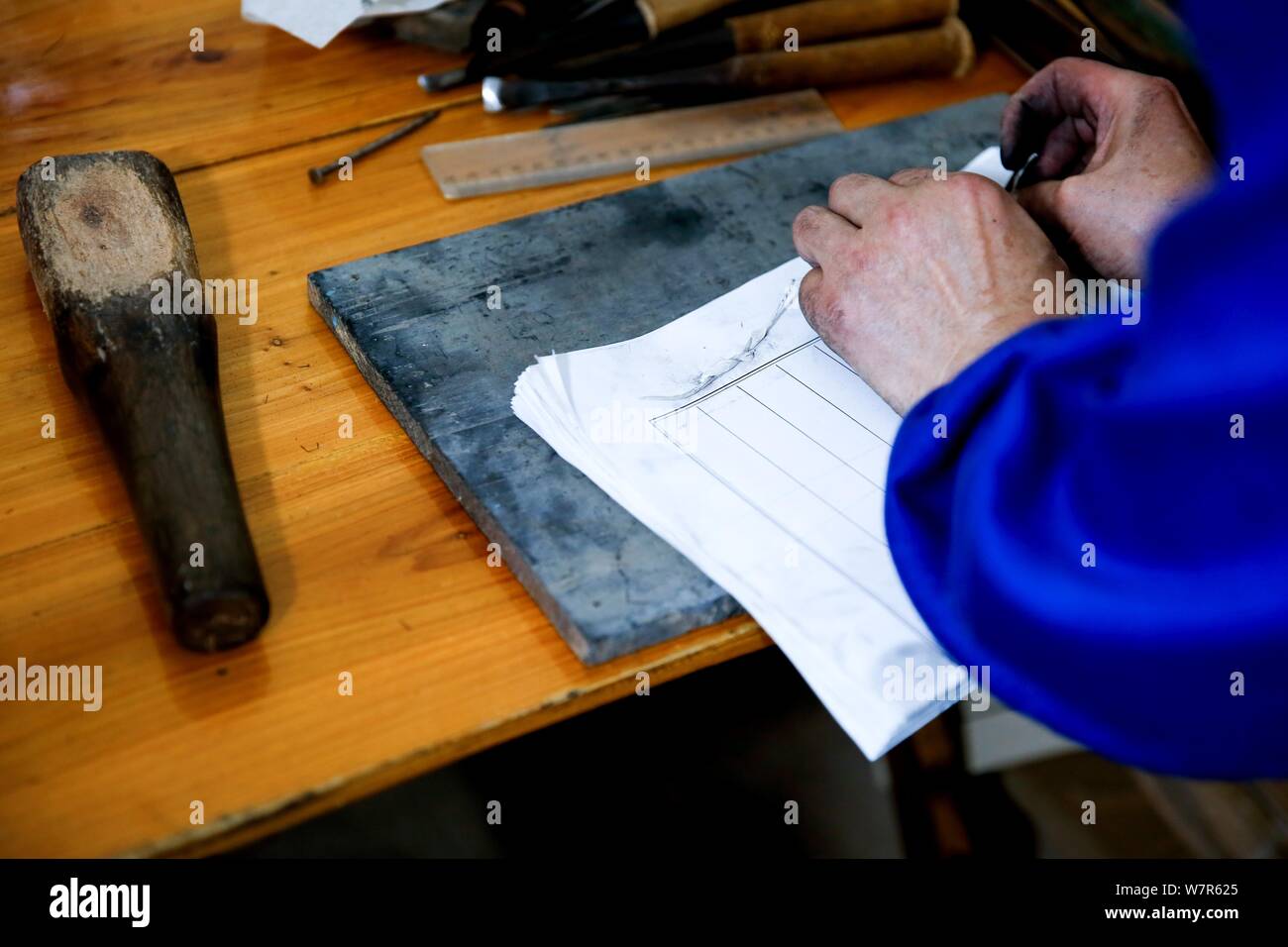 Chinese craftsman Xiao Shihua prepares to print a book through a wood typehead plate for movable type printing in Zhulin village, Tantou town, Shaoyan Stock Photo