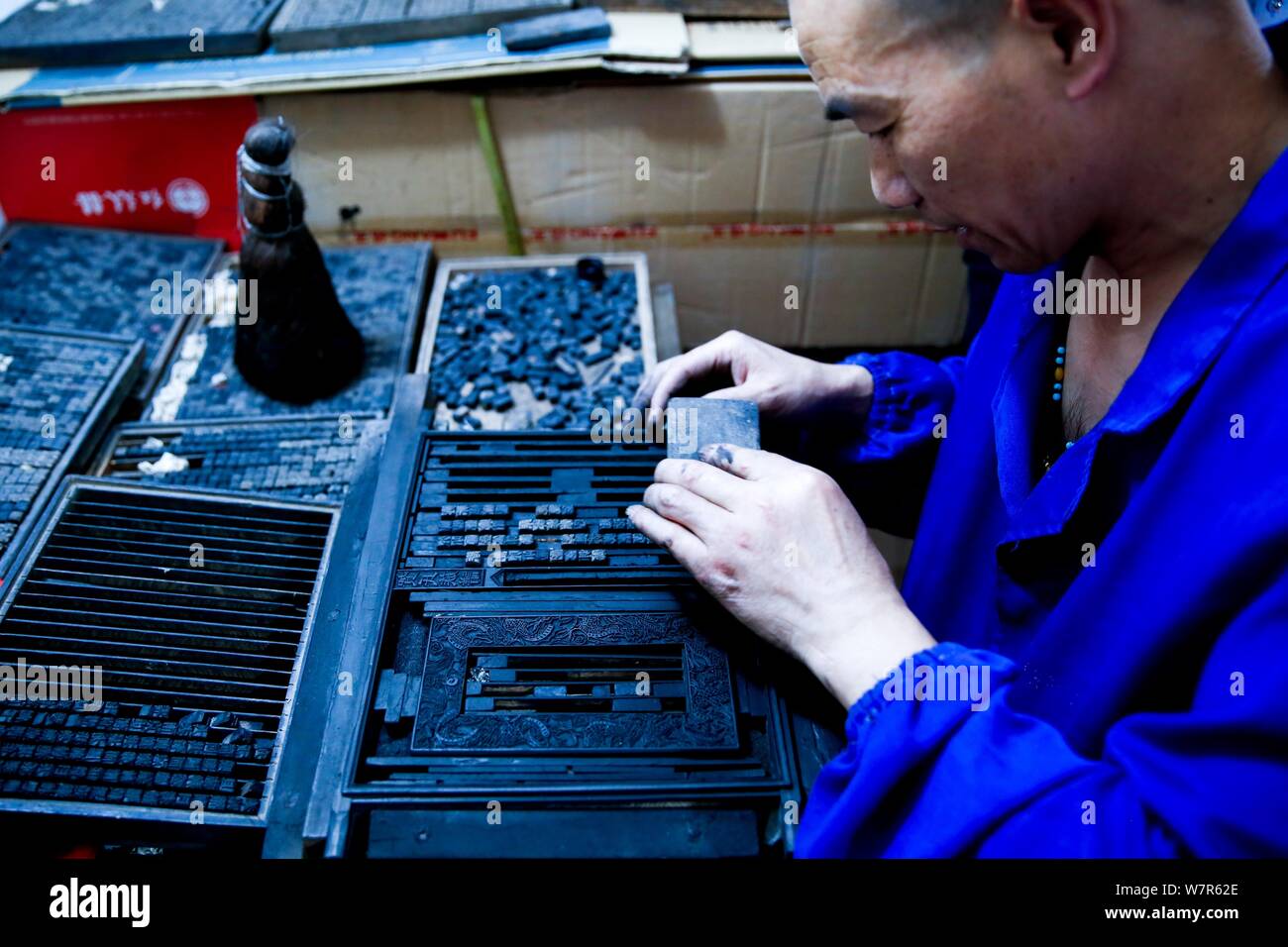 Chinese craftsman Xiao Shihua prepares to print through a wood typehead plate for movable type printing in Zhulin village, Tantou town, Shaoyang city, Stock Photo