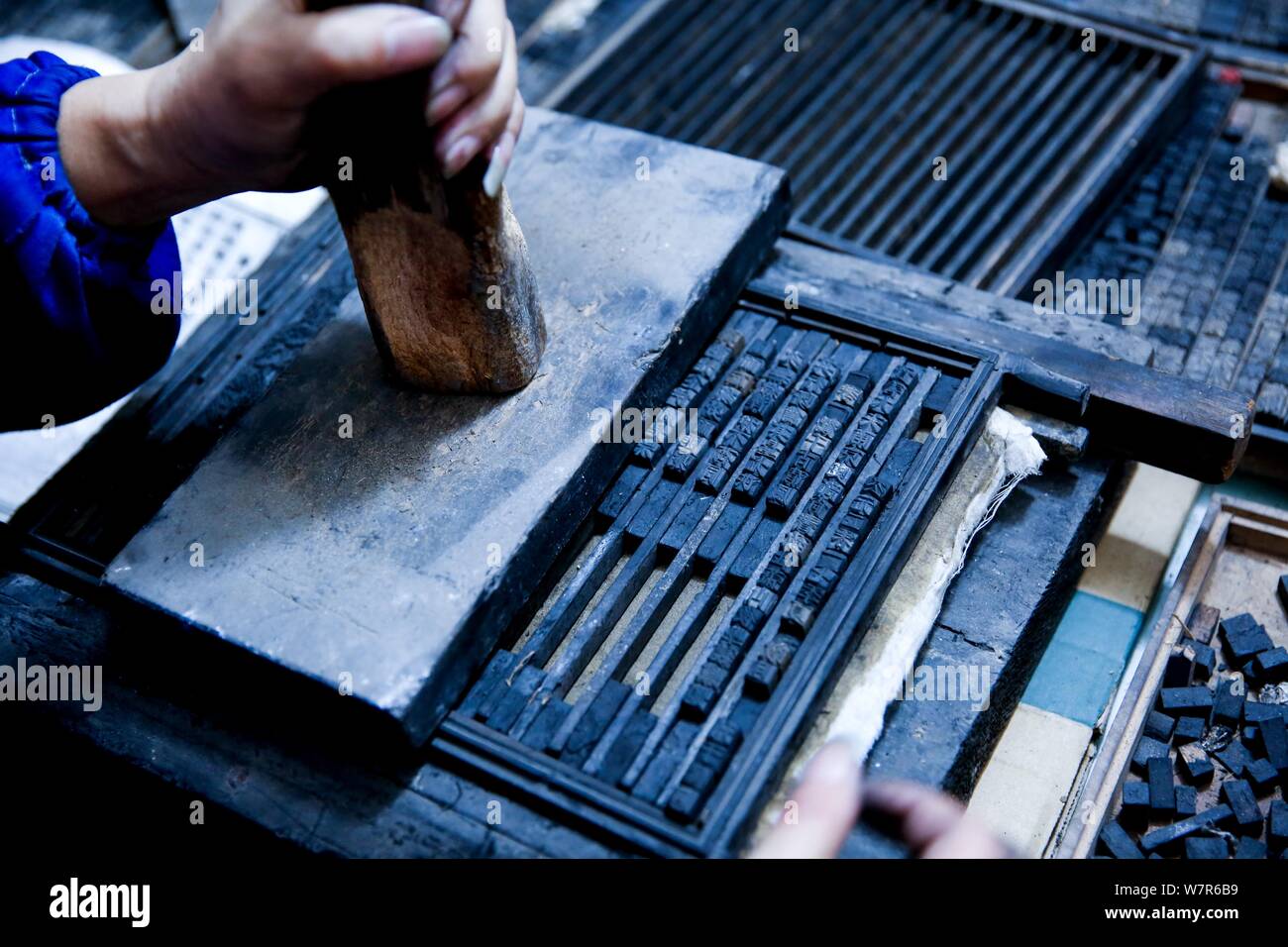 Chinese craftsman Xiao Shihua prepares to print through a wood typehead plate for movable type printing in Zhulin village, Tantou town, Shaoyang city, Stock Photo