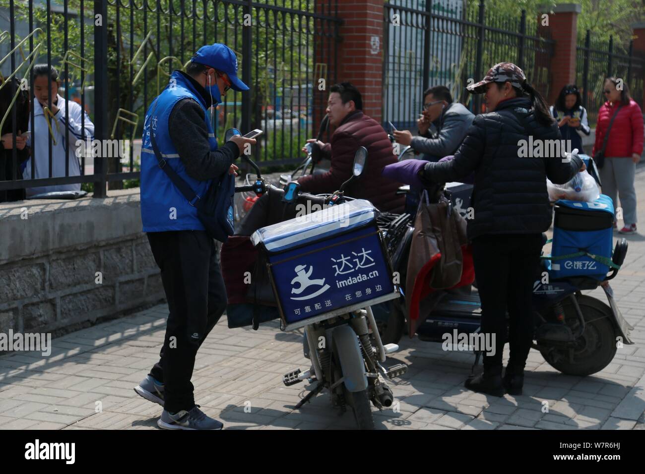 --FILE--Food delivery couriers of Chinese online food delivery companies wait for customers outsides a university in Ji'nan city, east China's Shandon Stock Photo