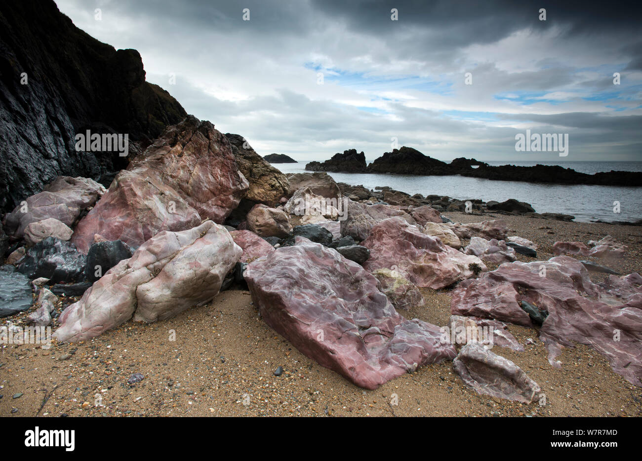 Pink Pre-Cambrian Quartzite boulders on a shingle beach, Llanddwyn Island, Anglesey, Wales, August 2012 Stock Photo