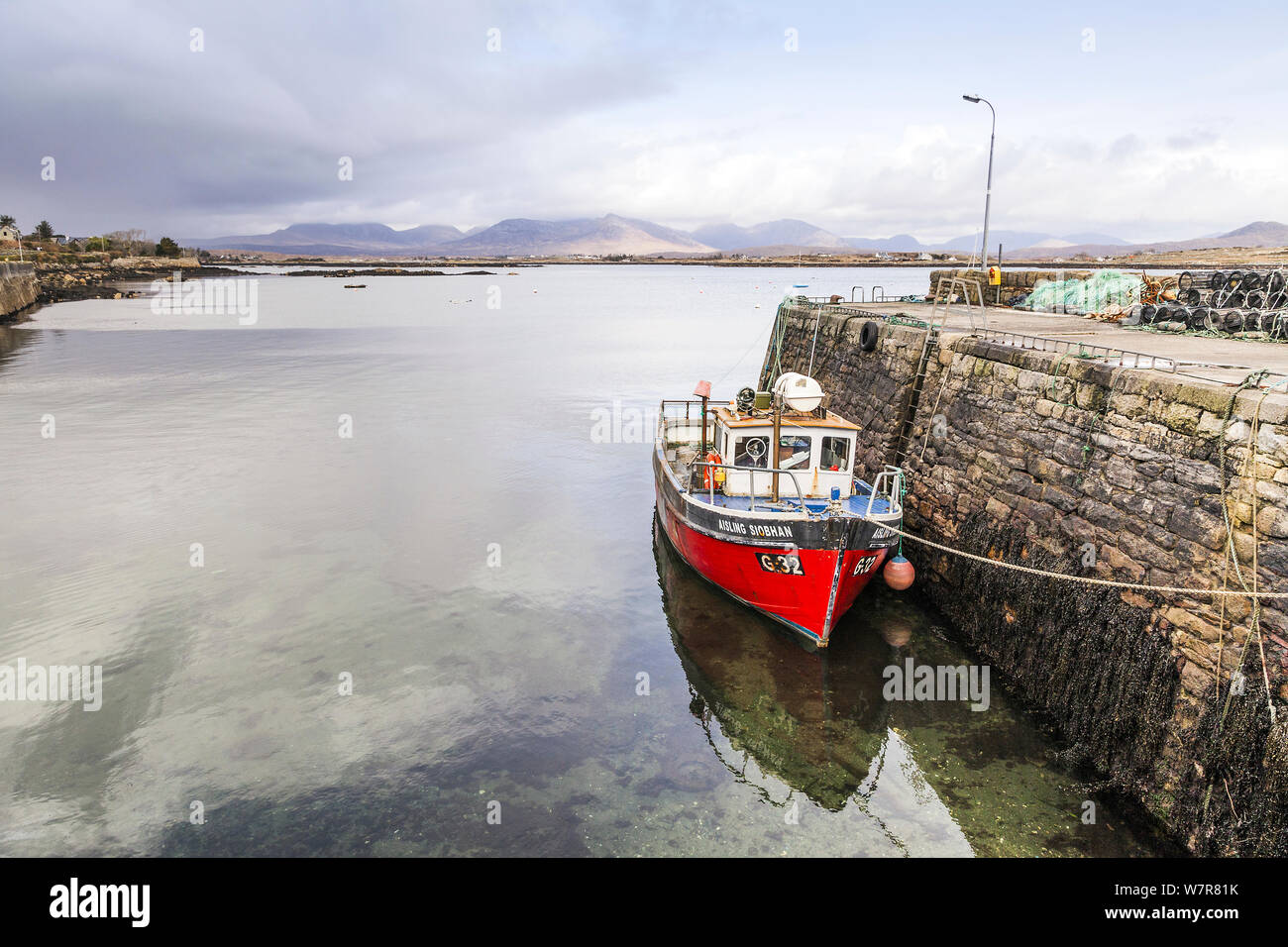 View over Roundstone Harbour, with fishing boat moored to the quay, Connemara, Republic of Ireland, March 2013. Stock Photo