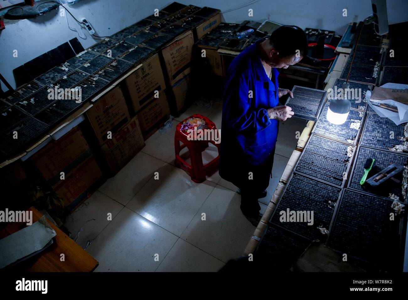 Chinese craftsman Xiao Shihua puts wood typeheads into a plate for movable type printing in Zhulin village, Tantou town, Shaoyang city, central China' Stock Photo