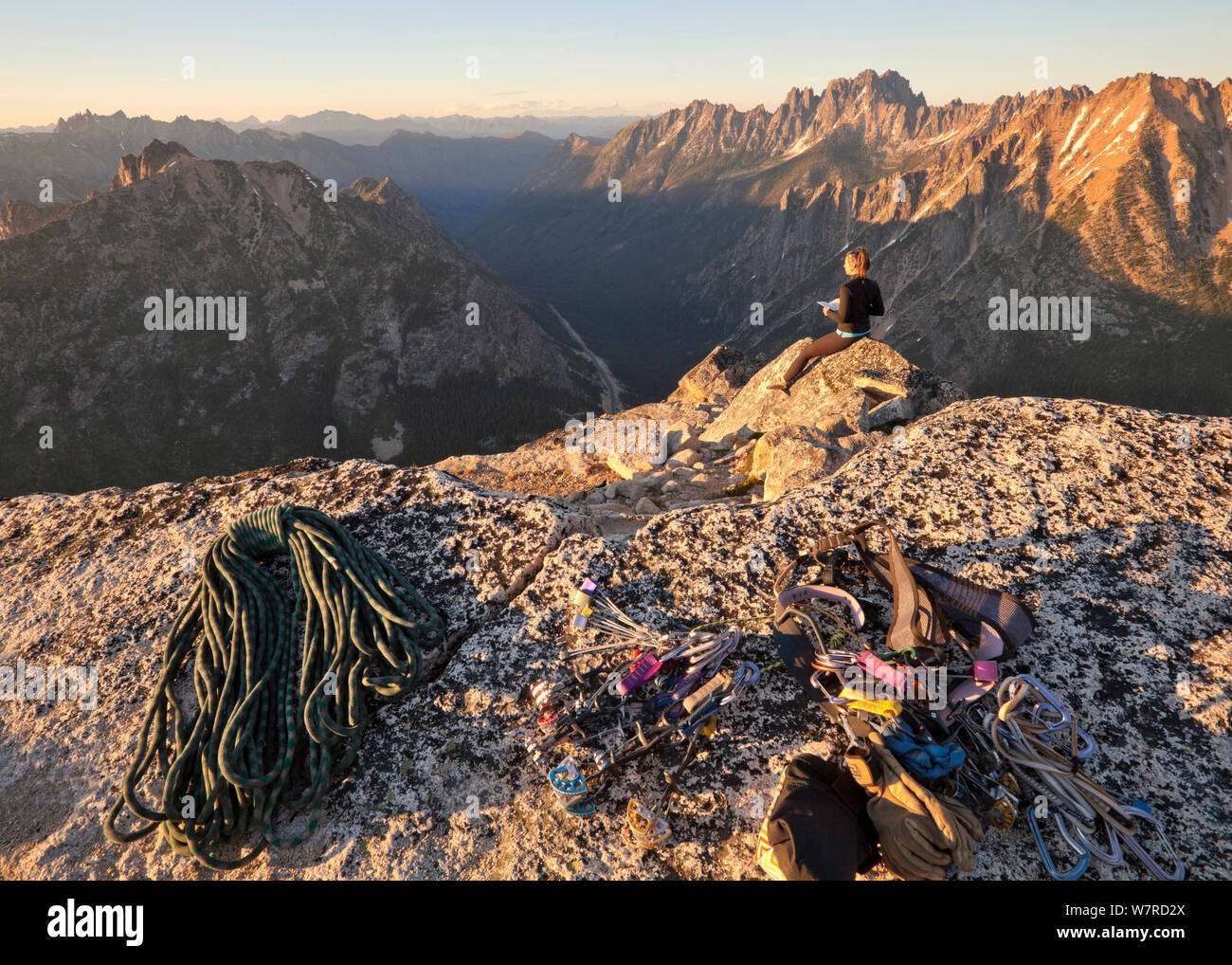 Woman enjoying the summit views at sunset after climbing to the summit of Liberty Bell via the Beckey Route, near Washington Pass in North Cascades, Washington, USA , July 2013 Stock Photo