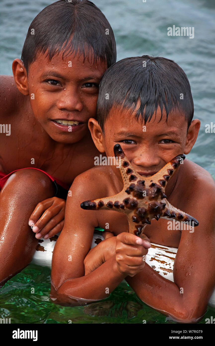 Children with a Chocolate Chips Sea Star (Protoreaster nodosus), Bilang Bilangang Island, Danajon Bank, Central Visayas, Philippines, April 2013 Stock Photo