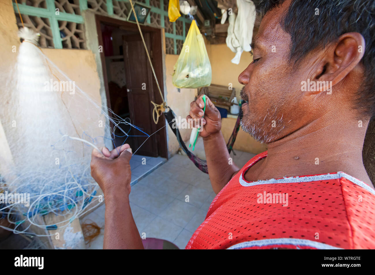 Man repairing plastic fishing nets, Batasan Island, Danajon Bank, Central Visayas, Philippines, April 2013 Stock Photo