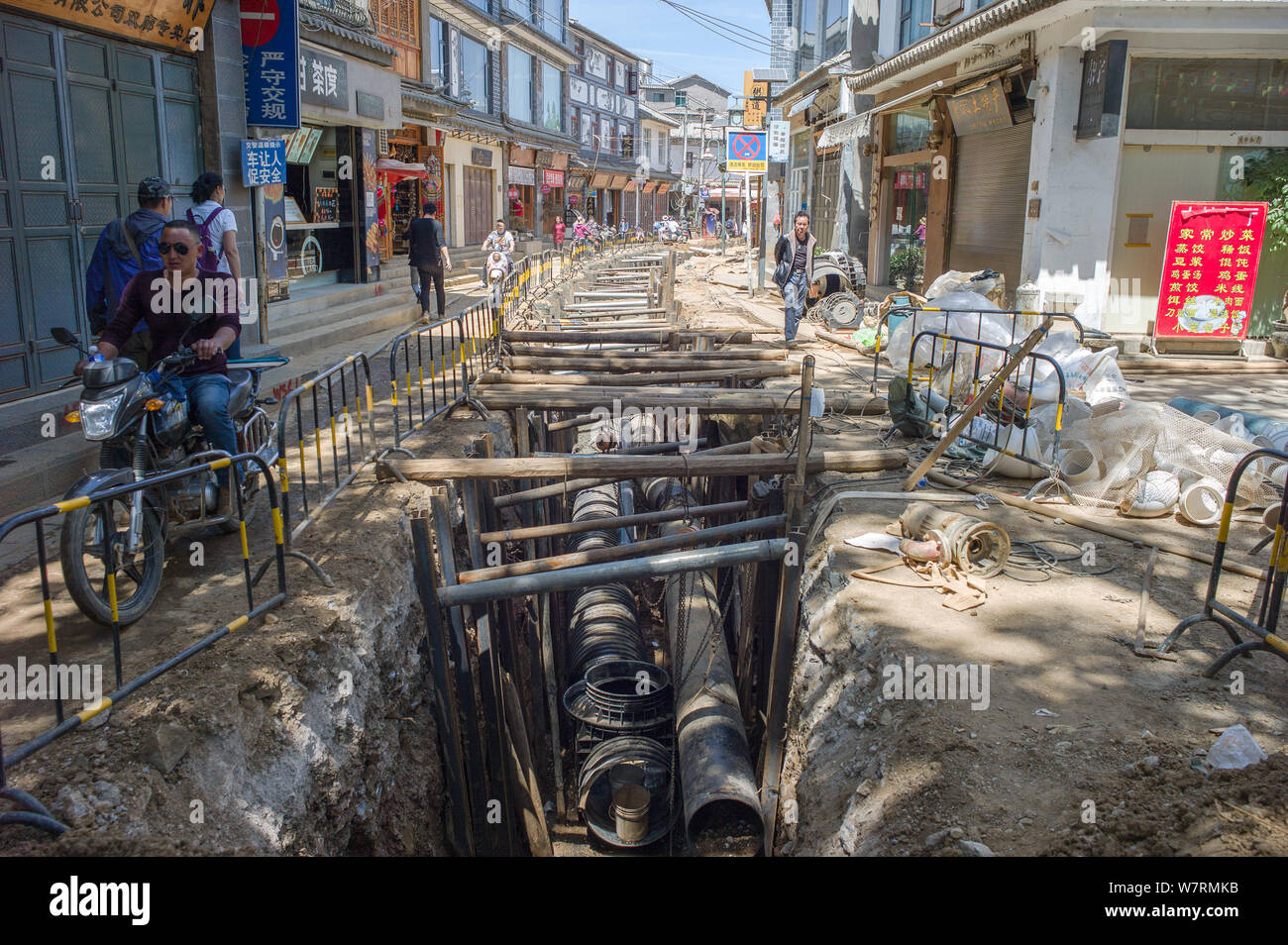 --FILE--Local Chinese residents and tourists pass by sewage pipes being ...