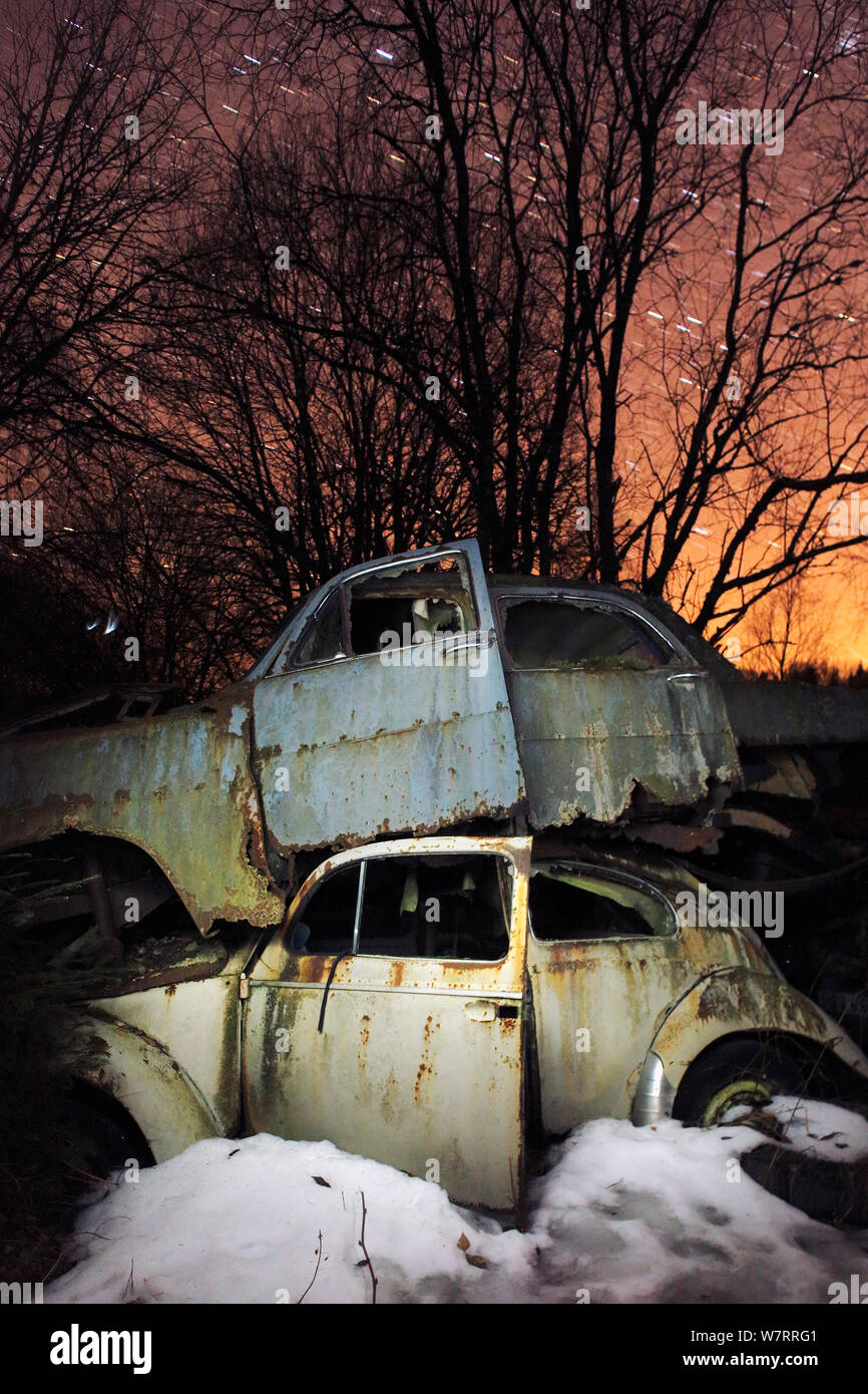 Old abandoned cars stacked on atop the other in 'car graveyard' at night, Bastnas, Sweden April Stock Photo