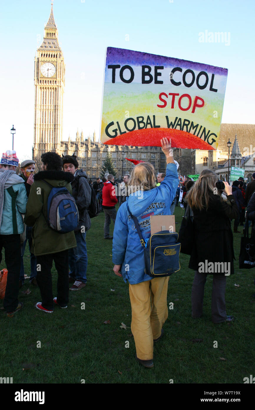 Environmental protester infront of houses of parliment holding up placard stating 'To be cool stop global warming' London UK Stock Photo