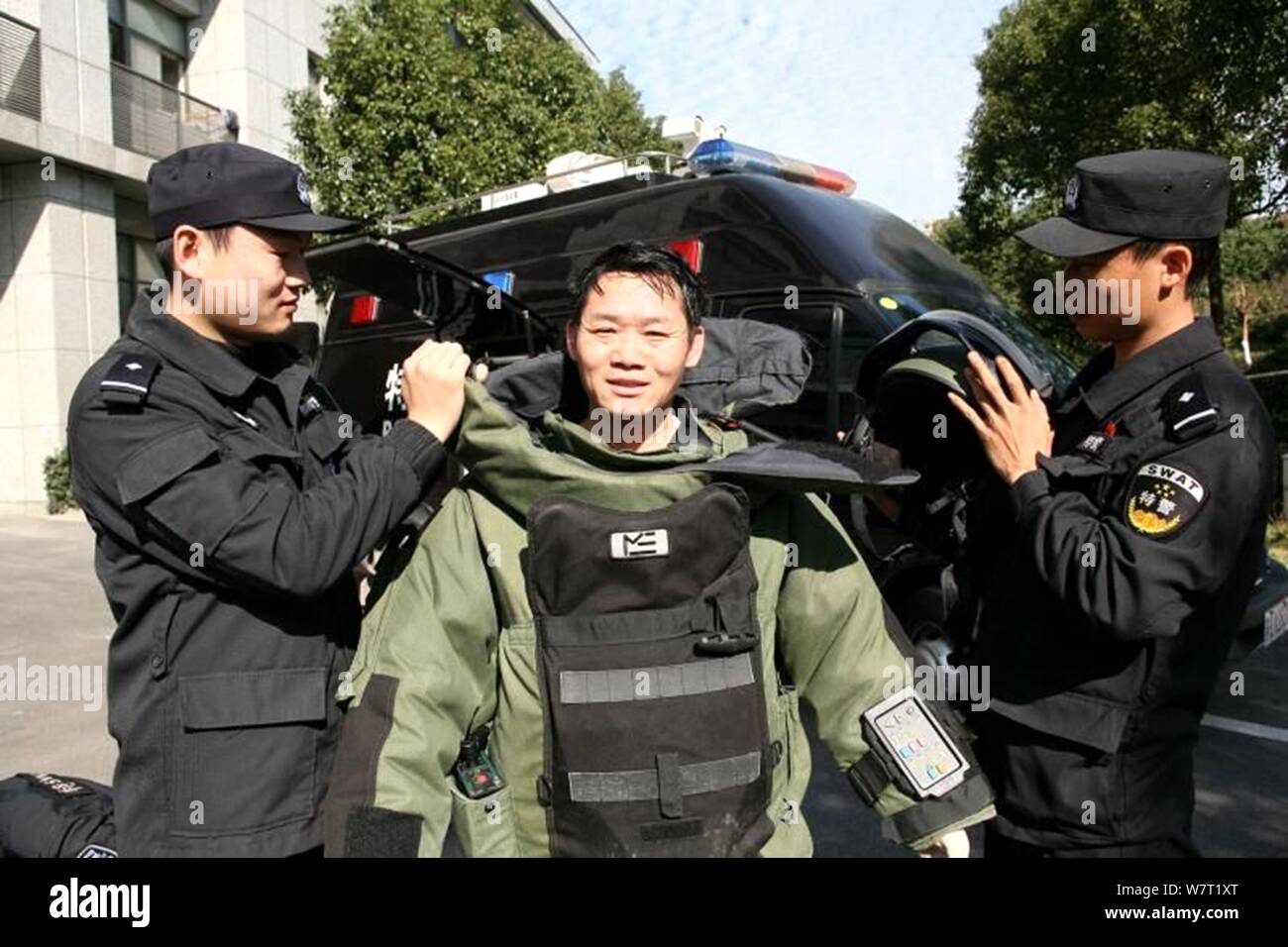 Police officers help Chinese explosive disposal policeman Luo Jinfang to wear a protective suit in Zhenjiang city, east China's Jiangsu province, 14 M Stock Photo