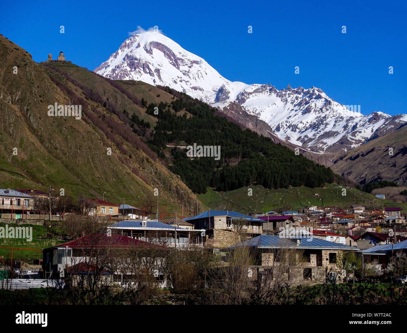 Peak of Kasbek-Qasbegi and village Gergeti near Stepanzminda-Kasbegi at Geogian Military Road , Mzcheta-Mtianeti, Georgia, Europe Stock Photo