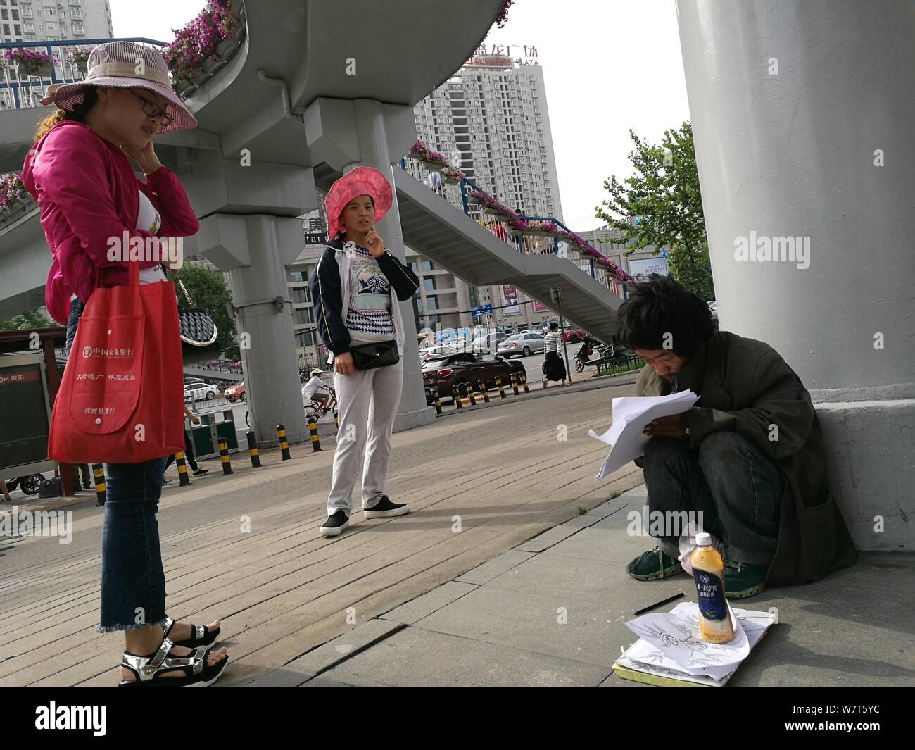 Homeless man Wang Xiaoming draws under a flyover in Xi'an city
