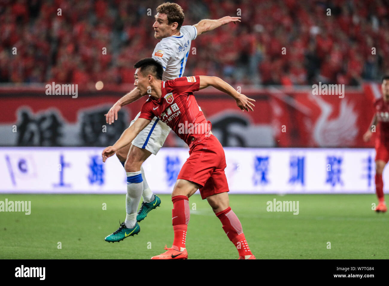 Australian football player Ryan McGowan, upper, of Guizhou Hengfeng Zhicheng, challenges with a football player of Shanghai SIPG in their 8th round ma Stock Photo