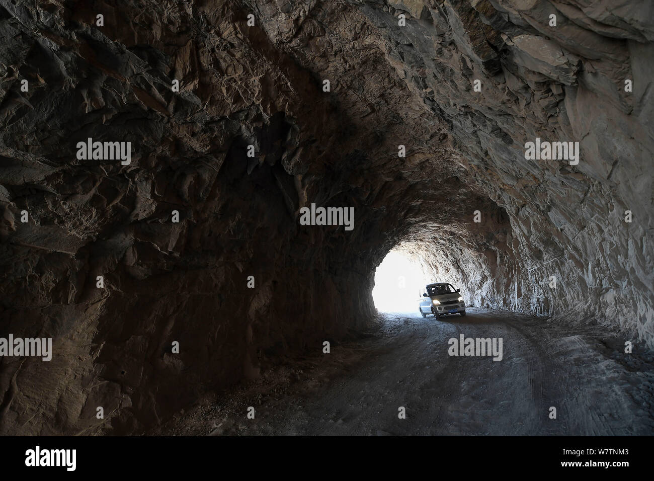 A car travels on the road carved by local villagers on the edge of a cliff on Taihang Mountains in Hongtiguan village, Pingshun county, Changzhi city, Stock Photo