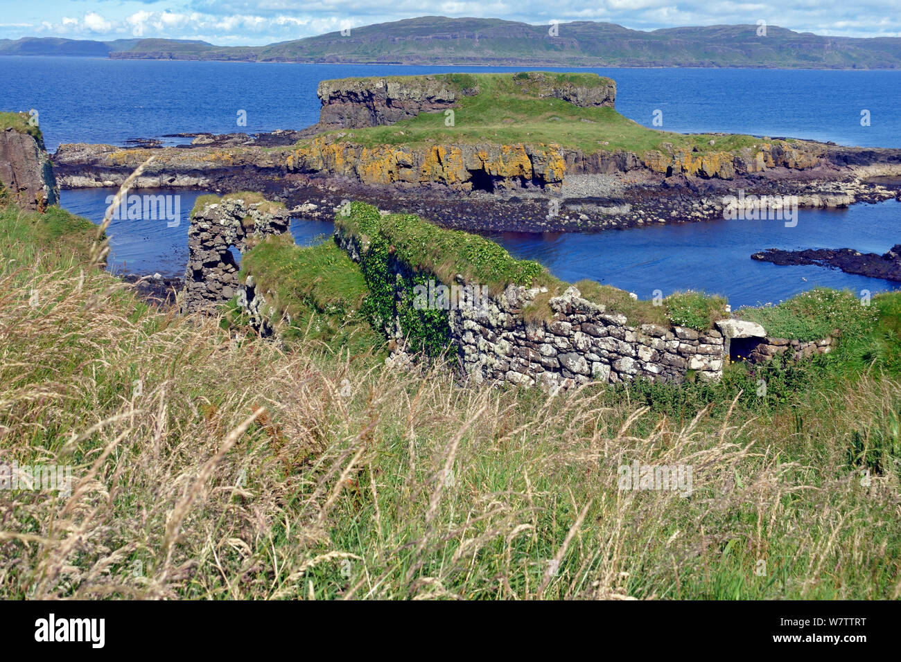 Curtain wall part of the defences of Cairnburgh Castle on Cairn nan Burgh Mor showing Cairn nan Burgh Beag and the western coastline of Mull behind Stock Photo