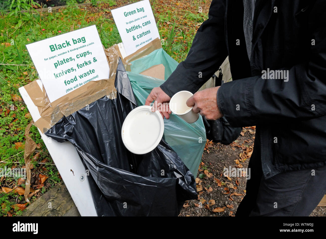 Man recycling cardboard mug and plate into the appropriate bag