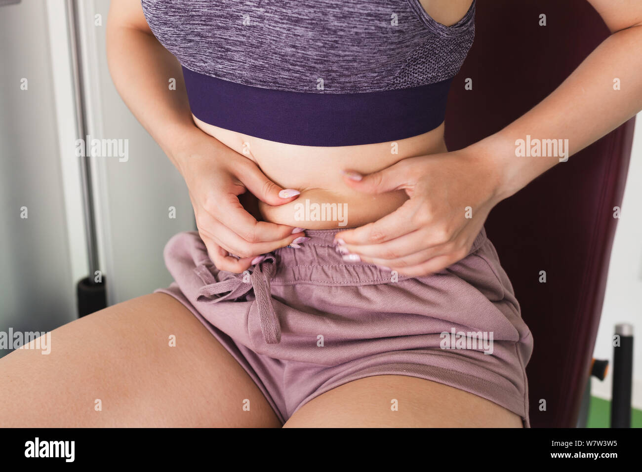 Young girl pinched herself at the waist to test fat level under skin. Skin fold test Stock Photo