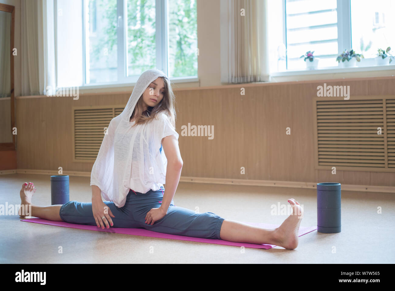 Young slim woman with blonde hair sitting on the yoga mat in horizontal ...