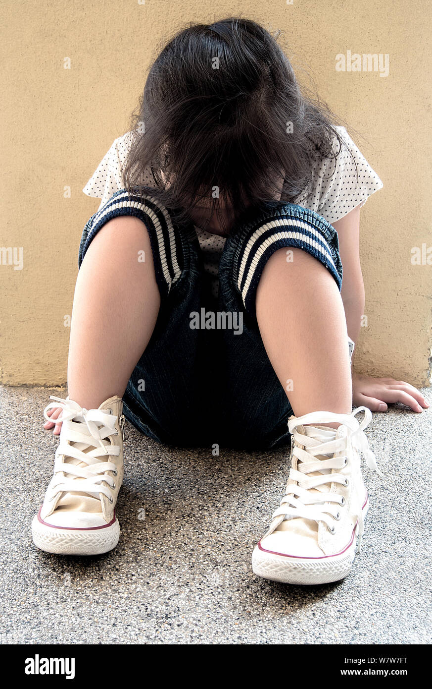 A Lonely girl sitting behind the concrete wall Stock Photo - Alamy