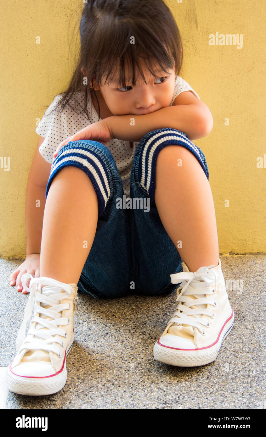 A Lonely girl sitting behind the concrete wall Stock Photo - Alamy