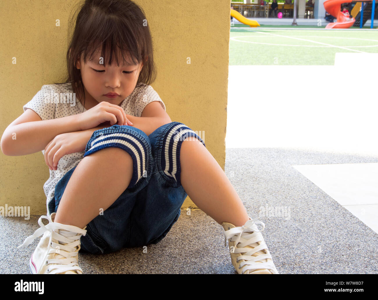 A Lonely girl sitting behind the concrete wall Stock Photo - Alamy