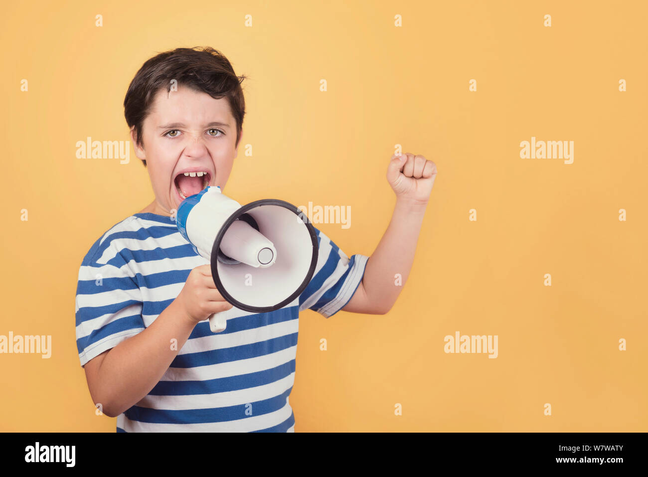 screaming child with megaphone against yellow background Stock Photo