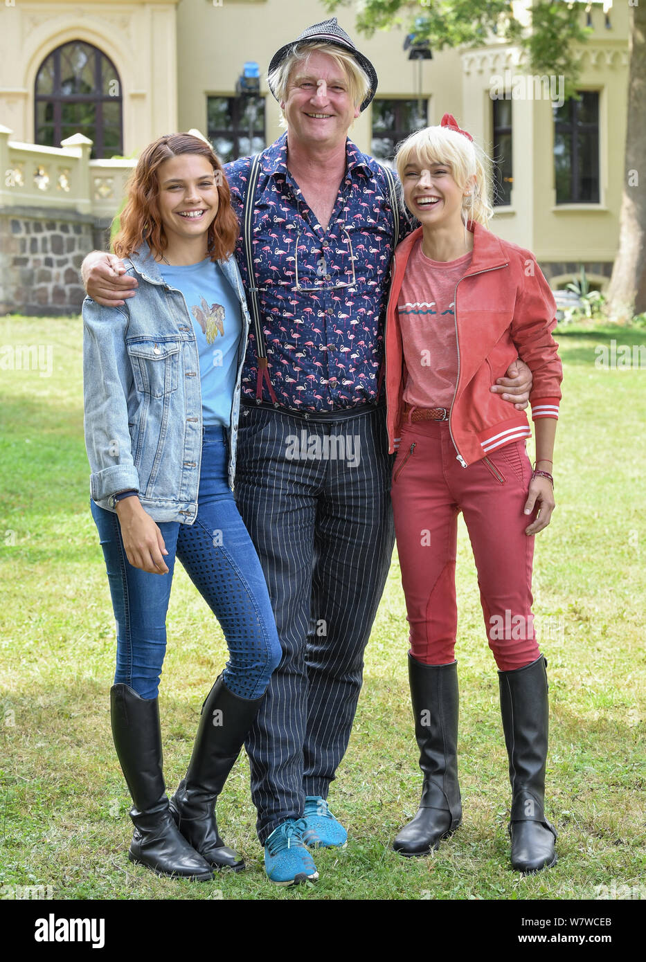 06 August 2019, Brandenburg, Reichenow: Actress Harriet Herbig-Matten (l) as Tina, director Detlev Buck and actress Katharina Hirschberg as Bibi stand on the set of the Amazon series Bibi and Tina in front of Schloss Reichenow. The shooting of the new Amazon Original Bibi & Tina is currently underway in the Berlin area. The live action series for the whole family accompanies the young witch Bibi Blocksberg and her best friend Tina on their adventures at the Reiterhof. The new series is to be shot by mid-August and will be available exclusively to Prime members from the first half of 2020. Phot Stock Photo