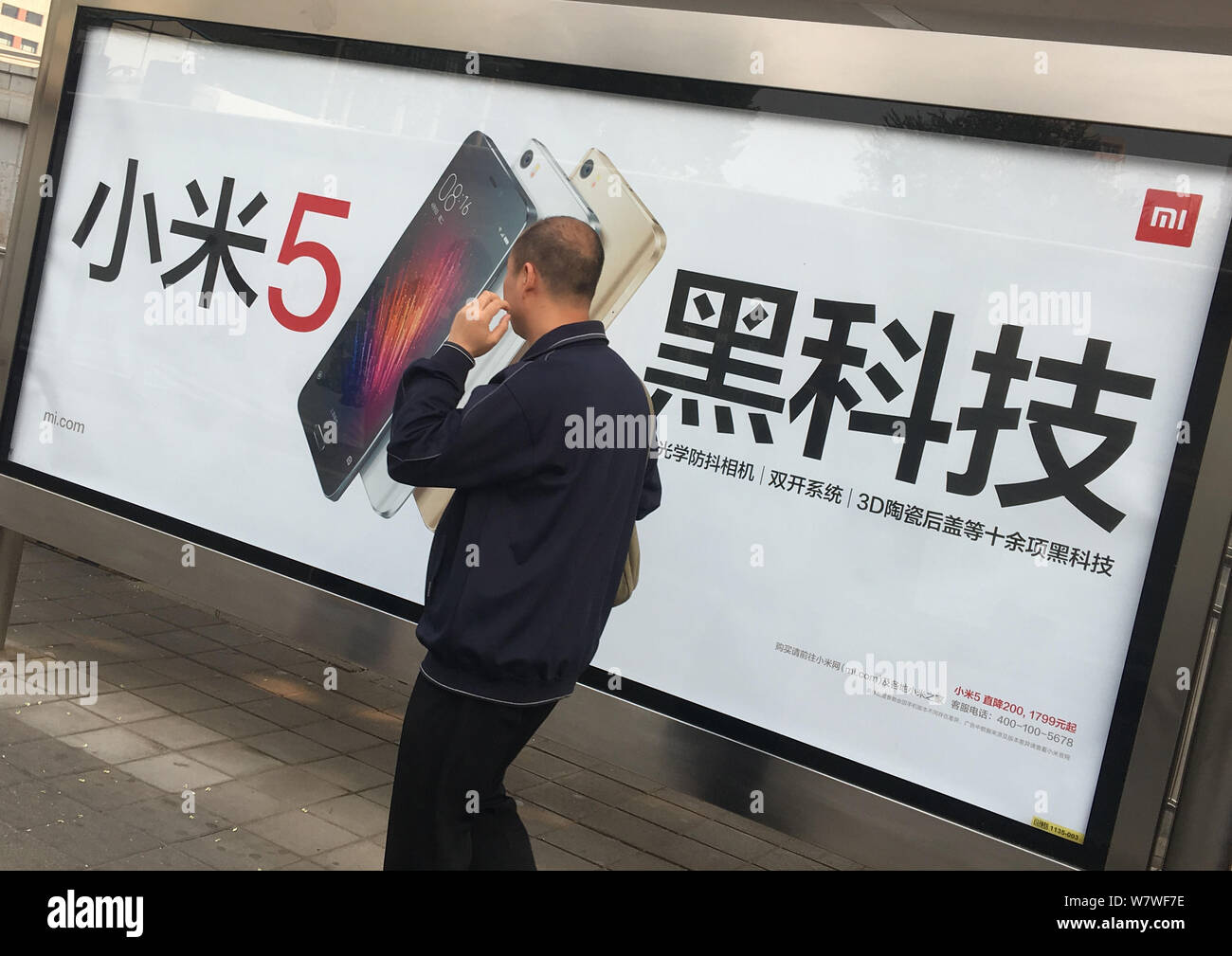 --FILE--A pedestrian walks past an advertisement for Xiaomi smartphones at a bus stop in Beijing, China, 22 September 2016.    Chinese smartphone vend Stock Photo