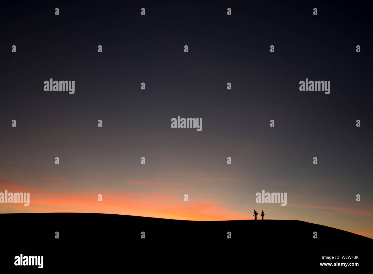 Two people silhouetted on sand dune ridge at sunset, White Sands National Monument, New Mexico, USA, December 2012. Stock Photo