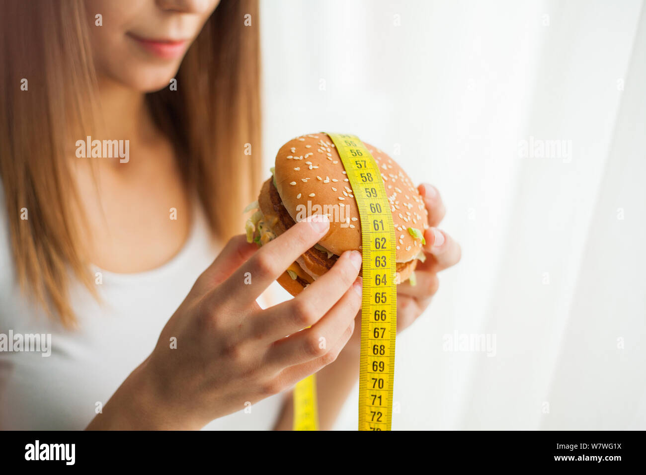Diet. Young woman with duct tape over her mouth, preventing her to eat