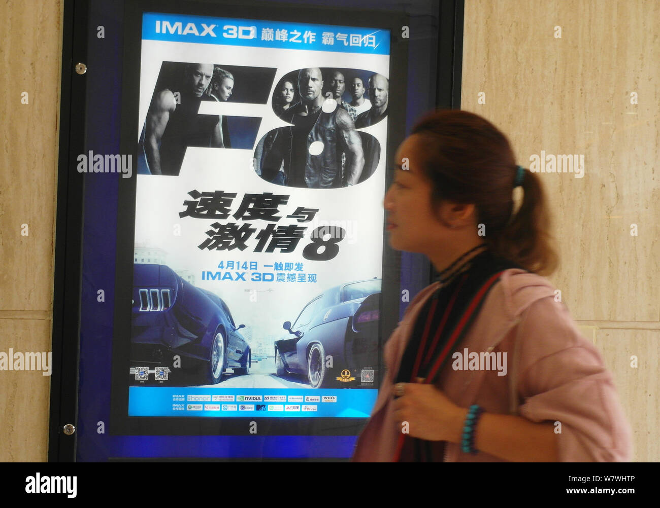 A Chinese filmgoer looks at a poster of the movie The Fate of the Furious,  known