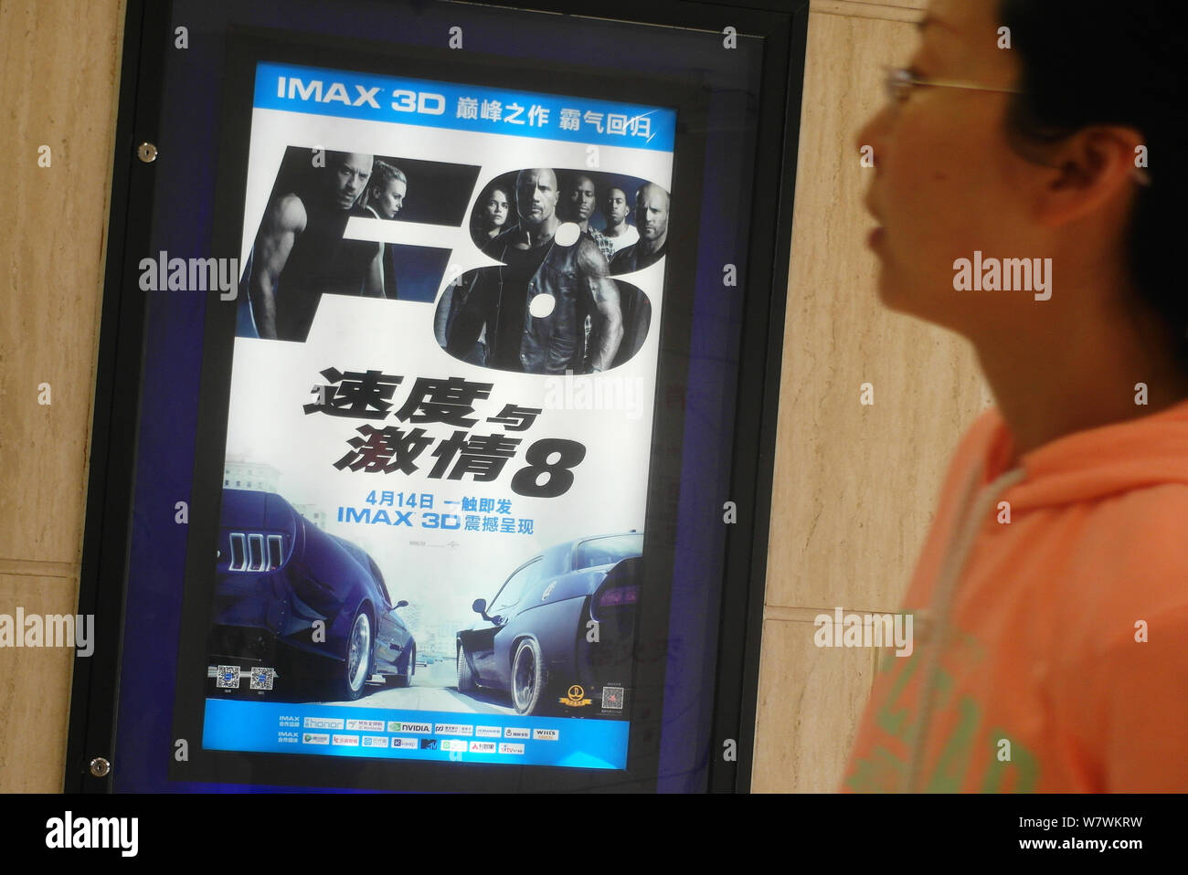 A Chinese filmgoer walks past a poster of the movie The Fate of