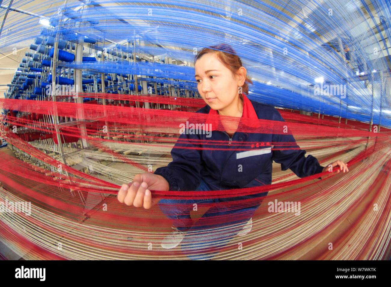 --FILE--A female Chinese worker checks production of yarn to make carpets at a factory in Jinghe county, northwest China's Xinjiang Uygur Autonomous R Stock Photo