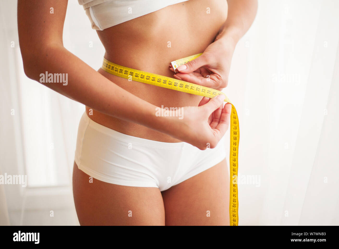 https://c8.alamy.com/comp/W7WNB3/slim-young-woman-measuring-her-thin-waist-with-a-tape-measure-W7WNB3.jpg
