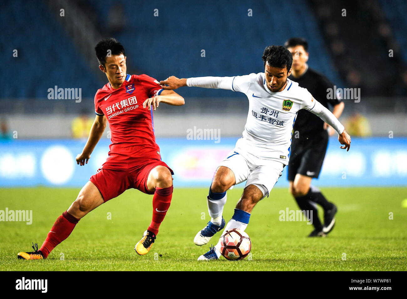 Australian football player Ryan McGowan of Guizhou Zhicheng, right, challenges a player of Chongqing Lifan in their fifth round match during the 2017 Stock Photo